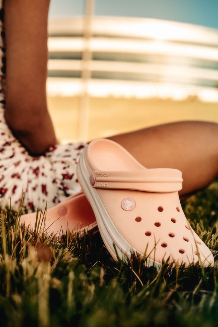 Close-up of pink Crocs with a summery vibe on a grassy lawn, perfect for outdoor fashion.