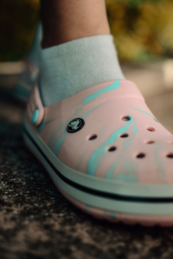 Detailed close-up of a stylish pink and blue clog worn with a white sock.